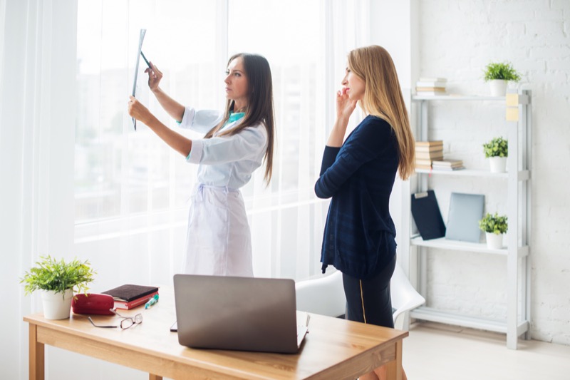 Doctor woman with white labcoat looking at x-ray radiographic results ct scan mri in hospital clinic