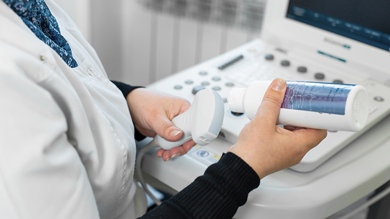 Doctor prepare an ultrasound machine for the diagnosis of a patient. Doctor puts media gel on an ultrasound transducer.